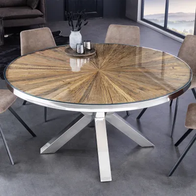 A round dining table with a wooden top and metal legs, surrounded by chairs in a dining room setting.
