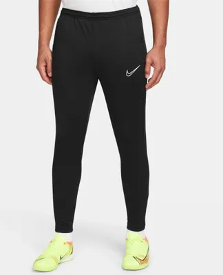 A person wearing black Nike pants and neon yellow soccer cleats.