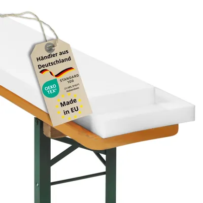 A white foam cushion placed on a wooden and green metal bench.
