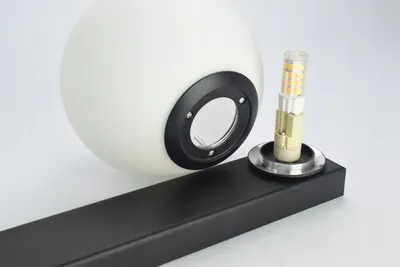 A white glass sphere light fixture and an LED bulb are shown on a black base against a white background.