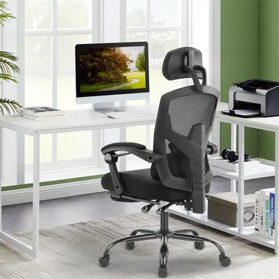 An office chair is placed in front of a desk with a computer and printer, in a well-lit room with a large window.