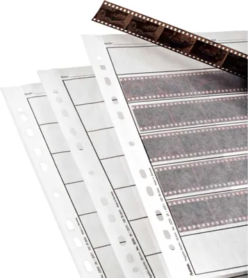 Several sheets of negative sleeves are stacked, with a strip of film resting on top.