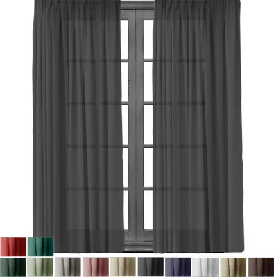 A pair of dark gray sheer curtains hanging in front of a window with a wooden frame.