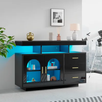 A modern black sideboard with LED lighting, displayed in a room setting with a plant and a telescope visible.