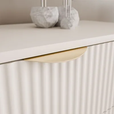 A close-up shot of a drawer handle on a fluted dresser.