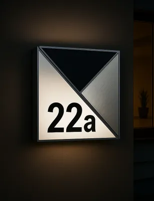 A modern, illuminated house number sign mounted on a dark wall.