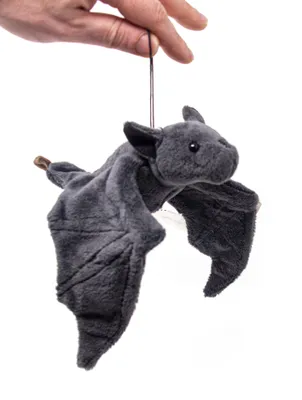 A hand holding a string attached to a stuffed bat toy.