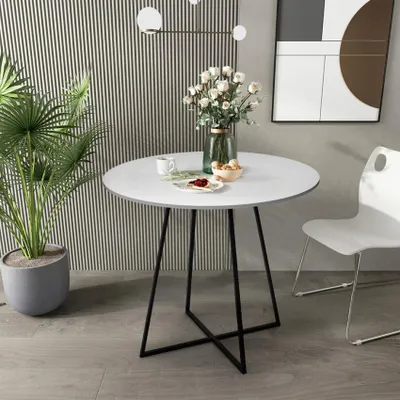 A round white dining table with black metal legs, set in a modern room with a striped wall and a white chair.