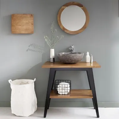 A bathroom vanity with a sink, mirror, and laundry basket.