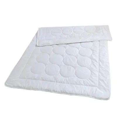 A white duvet with a circular pattern is laid out on a white background.