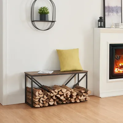 A firewood rack with a seat is placed next to a fireplace, with a yellow cushion on top.