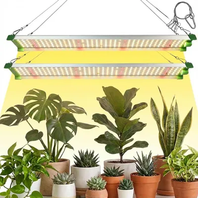 Two LED grow lights are suspended above a collection of potted houseplants.