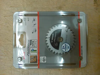 A Bosch circular saw blade in its retail packaging, placed on a wooden surface.
