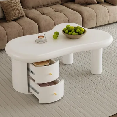 A white coffee table with two open drawers, placed on a rug in front of a sofa.