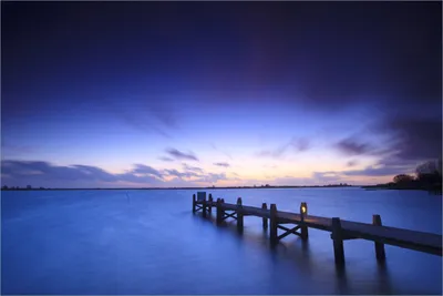 Produktbild von Wallario Premium Vliestapete Fototapete Steg bei Abenddämmerung - Blauer Himmel bei Nacht in der Größe 400 x 267 cm, extra dick, wird in 5 Teilen geliefert