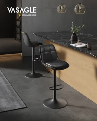 Two black bar stools are shown in a modern kitchen setting with a marble countertop and pendant lights.