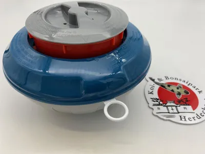 A pool chemical dispenser and a sticker are placed on a white surface.