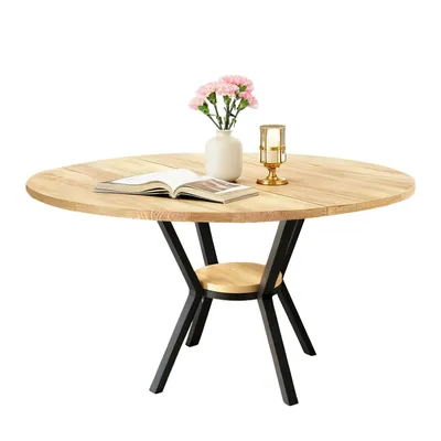 A round wooden dining table with a black metal base and a small shelf.