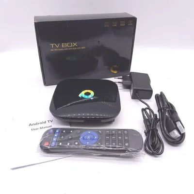 A TV box, remote control, power adapter, and cables are laid out on a white surface, with the product's box in the background.