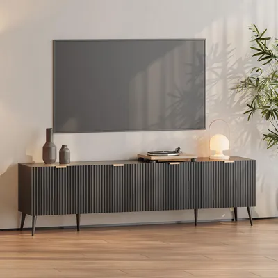 A modern media console with a television mounted above it, set in a well-lit room with a plant.