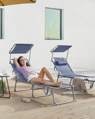 A woman relaxing on a blue chaise lounge outdoors, with another chaise lounge in the background.