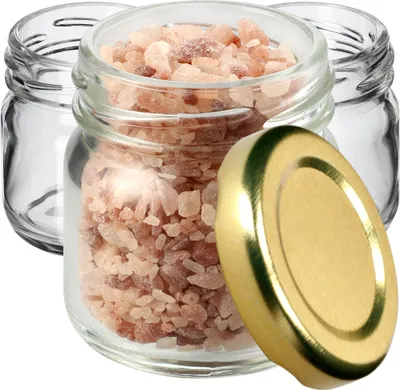 Three small glass jars, one filled with pink salt, and a gold lid.