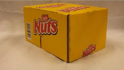 A yellow cardboard box with the 'Nuts' logo printed on it, placed on a light-colored surface.