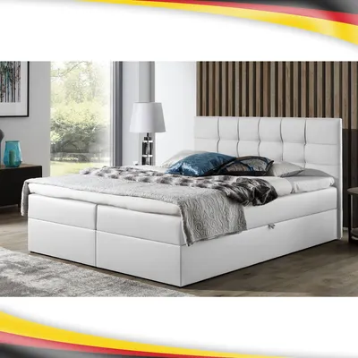 A white boxspring bed with a tufted headboard is shown in a bedroom setting.
