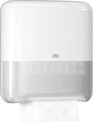 A white Tork Matic hand towel dispenser with a transparent lower section showing the towel roll inside. A portion of the paper towel is dispensed at the bottom.