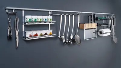 A kitchen rail system with various utensils and spice jars mounted on a gray wall.