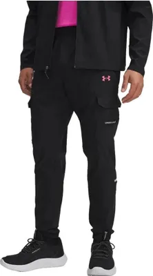 A person wearing black Under Armour cargo pants and a black jacket over a pink shirt.