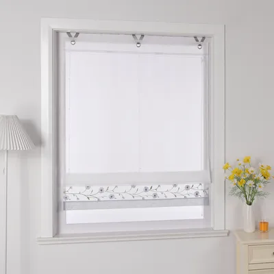 A white Roman blind with a floral pattern is shown hanging in a window.