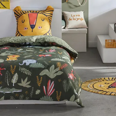 A child's bed with jungle-themed bedding and a lion-shaped pillow.