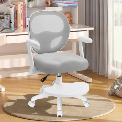 A gray and white ergonomic office chair for children is shown in a room with a desk and books in the background.