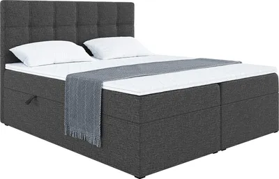 A dark gray upholstered boxspring bed with a headboard, two white pillows, and a gray throw blanket.