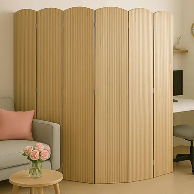 A room divider is placed next to a sofa and a small table with flowers, with a desk and computer visible in the background.
