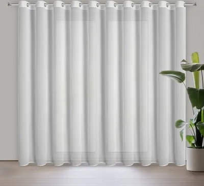 A white sheer curtain hangs in front of a window, with a potted plant to the right.