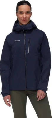 Dame trägt die "Alto Guide HS Hooded Jacket" von Mammut; dunkelblau; mit Kapuze; in aufrechter Position.