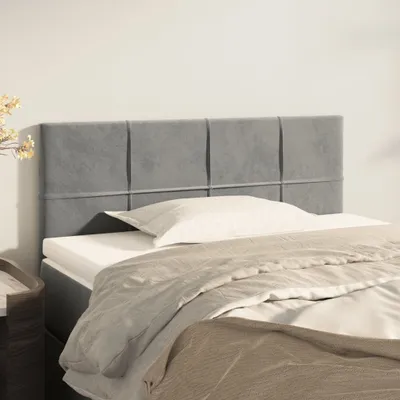 A close-up view of a bed with a grey upholstered headboard.