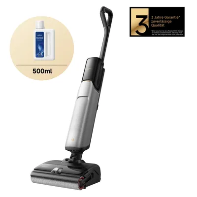 A cordless stick vacuum cleaner with a bottle of cleaning solution and a warranty badge.