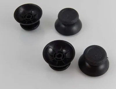 Four black joystick caps for a game controller are arranged on a white surface.
