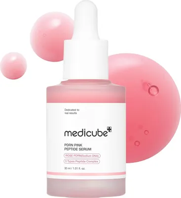 A bottle of Medicube PDRN Pink Peptide Serum with pink liquid droplets around it.