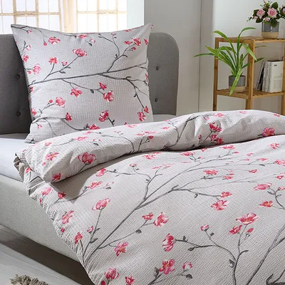 A close-up view of a bed with a duvet cover and pillow featuring a floral pattern.