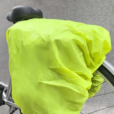 A close-up of a bicycle seat covered by a bright yellow rain cover.