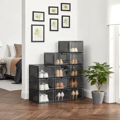 A collection of clear plastic shoe boxes stacked in a stair-like arrangement next to a bed in a room.