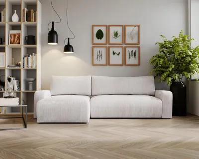 A modern living room with a white sectional sofa, bookshelf, and artwork.