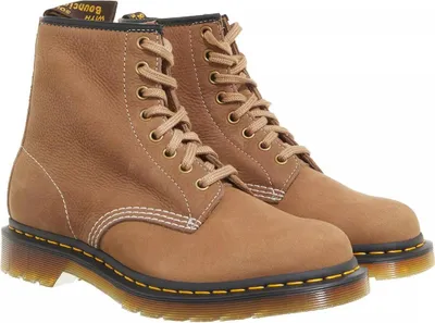 A pair of brown Dr. Martens boots on a white background.