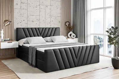 A bedroom scene with a black upholstered boxspring bed as the main focus.