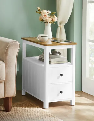A side table with drawers next to a sofa, decorated with flowers and a tablet.