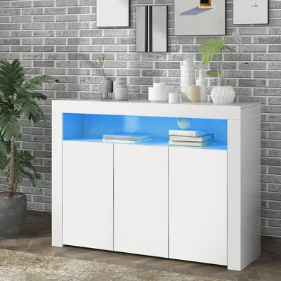 A white sideboard with blue LED lighting is displayed in a room with a brick wall background and a plant.